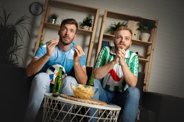 Focused young guys watch a key moment of the football match on TV
