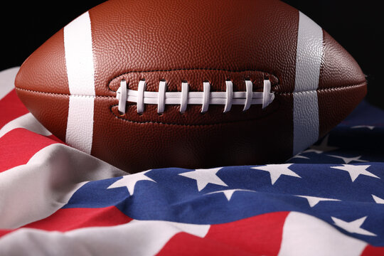 American football ball and USA flag. Sport game. Super bowl in US. Football ball Close Up macro photography with copy space.