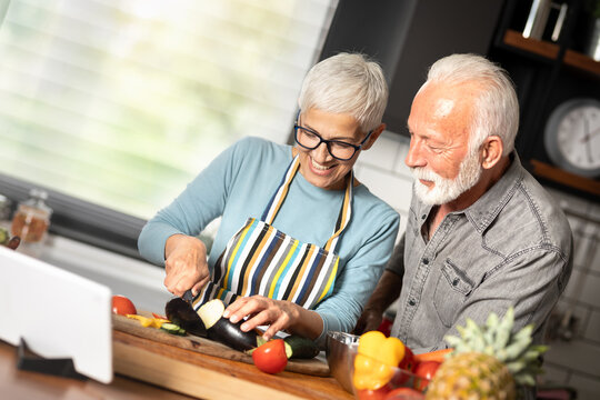 Senior couple reading food blog on digital tablet cooking