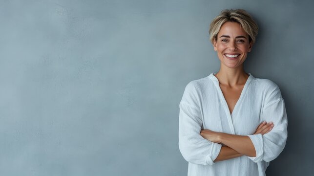 A smiling woman confidently poses against a gray background, showcasing her bright personality and modern style, exuding positivity and approachability in her expression.