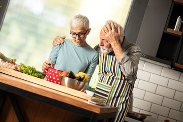 Verry disappointed senior couple looking in pot of failed meal.