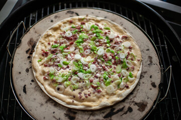 Traditional Flammkuchen on grill with crispy crust and toppings, rustic outdoor cooking