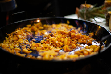 Flambéed apple pieces with blue flame in pan on barbecue grill, smoky grilled dessert