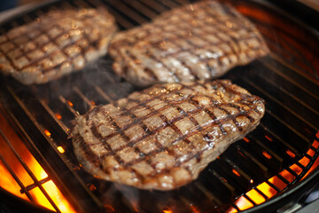 Juicy steak sizzling on grill with flames, classic barbecue meat close-up