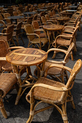 Numerous empty rattan chairs and small tables arranged on an outdoor patio, characteristic of a cafe or restaurant seating area