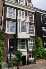 A traditional Dutch townhouse with a distinctive bay window and dormers, flanked by other historical buildings