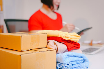 A young woman takes photos of clothes to sell online, holding a striped sweater and taking selfies...