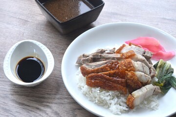 slice roasted duck couple crispy pork topping rice with pink pickled ginger and boiled cabbage dressing sweet soy sauce on plate 