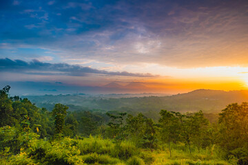 Serene Mountain Landscape at Sunrise with Misty Forest and Colorful Skies.