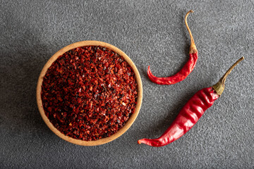 Red pepper flakes.Red chili peppers in wooden bowl on black background.Dried chili peppers
