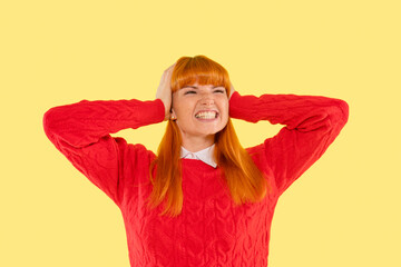 Woman expressing frustration while holding her head, wearing a bright red sweater against a vivid...