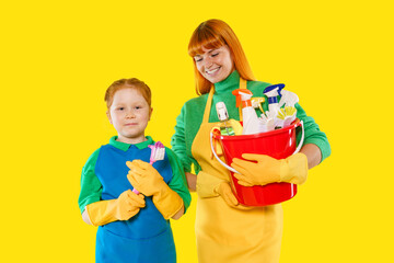 Mother and daughter cleaning together against a bright yellow background, showcasing teamwork and...