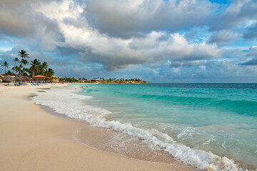 The idyllic beauty of Divi Beach, Aruba, with its gentle waves, swaying palm trees, and inviting resorts.