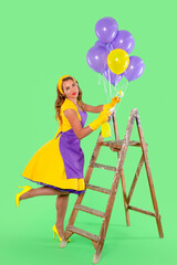 Woman in vibrant dress posing with balloons while climbing a ladder in front of a bright green...