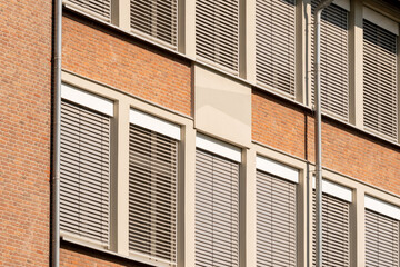 Modern building facade featuring venetian blinds and red brick wall
