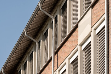 Modern building exterior showing rain gutters and window shutters on brick facade