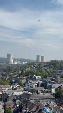 Panoramic, scenic aerial view of Huy city, mountains and chimneys of nuclear power plant. Airplane is flying above and descending towards Liege airport. View from Fort de Huy. Huy, Belgium