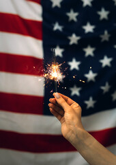 Sparklers in hand on an American Flag background. Independence day United States. Celebration 4th...