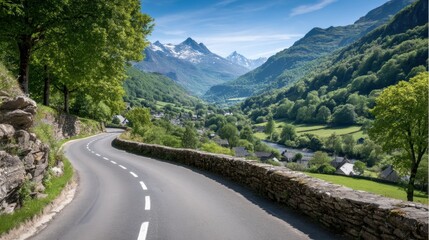 A winding mountain road curves through lush green valleys with distant snow-capped peaks under a bright blue sky.