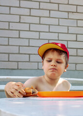 A little boy takes a big bite of a bun, his mouth full, his cheeks puffed out