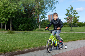 A little boy rides a bicycle in the park during the summer