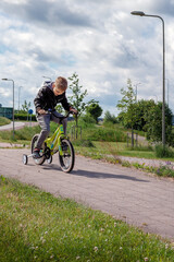 A little boy is riding his bike down a hill in the park