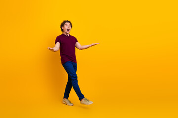 Energetic young man posing against a vivid yellow background expressing surprise and enthusiasm in casual trendy attire