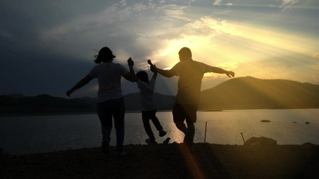 Happy family with three children running around at sunset in summer.