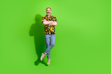 Fototapeta premium Cheerful middle aged man in a vibrant summer shirt posing against a solid green background, exuding fun and style