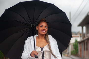 Young woman holding umbrella enjoying rain in the city