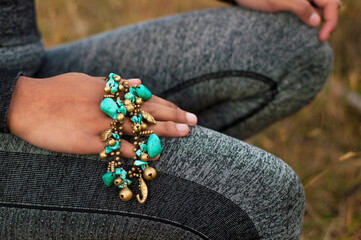 Woman wearing turquoise and brass bracelet meditating outdoors