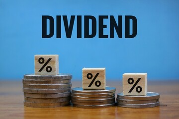 Financial Dividend Concept with Percentage Cubes and Coins on blue Background