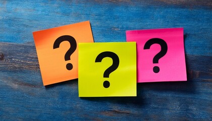 assorted colorful sticky notes with question marks scattered on a wooden surface