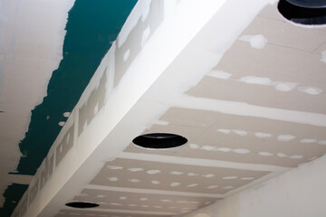 Suspended ceiling in a restaurant with holes showing large ventilation pipes, ceiling unfinished