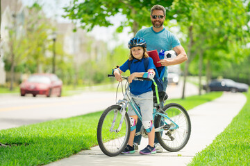 Obraz premium Fathers day and summer family weekend. Father teaching son ride on bike. Father and son ride a bicycle. Father support and helping son. Fathers day concept. Father and son friends. Child care.