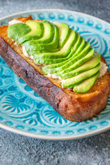 Toasted white bread with labneh spread and avocado slices on blue plate