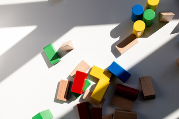 Colorful wooden blocks and shapes with shadows on white surface