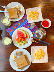 Healthy breakfast spread in hotel concept no people. Simple meal of fresh fruits, toasted bread, fruit juice. Top down angle flat lay of breakfast setting, wooden table. Travel concept La Paz, Bolivia