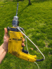 Adult man holding drill with damaged power cord outdoors