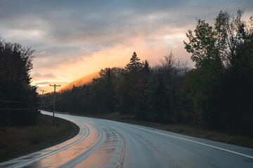 Fototapeta premium view of a curved road in a mountainous area with a wet surface under a sunset sky