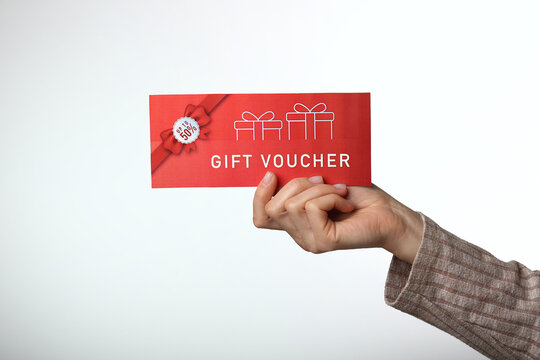 Top view of woman holding gift voucher lettering on white background