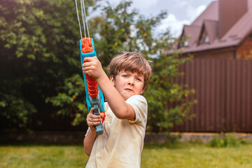 Happy child playing with water gun outdoors on a sunny day. Perfect summer activity, game, fun, and playful childhood concept. Great image for themes like outdoor fun, summer games, kids&rsquo; activities.