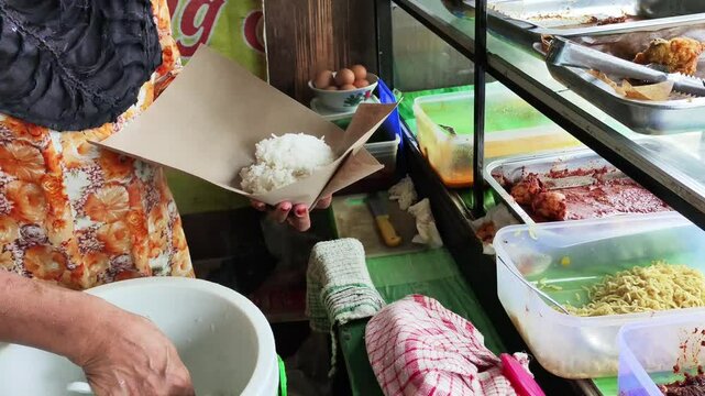 Nasi Campur seller are serving buyers, Nasi Campur seller are wrapping food ordered by customers.
