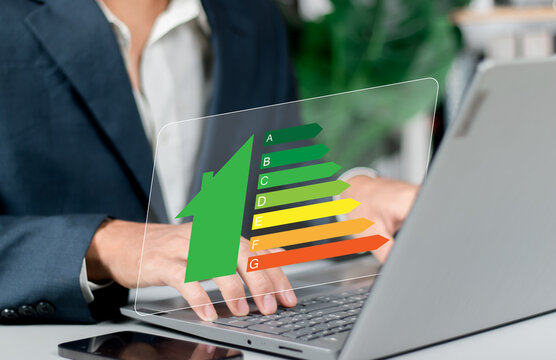 Person hand holding house icon with energy efficiency scale image on blue bokeh background, Concept of ecological and bio energetic house. Energy class.