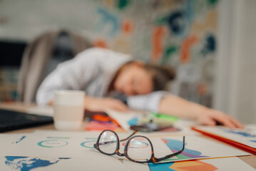 Exhausted businesswoman sleeping at workplace after working late