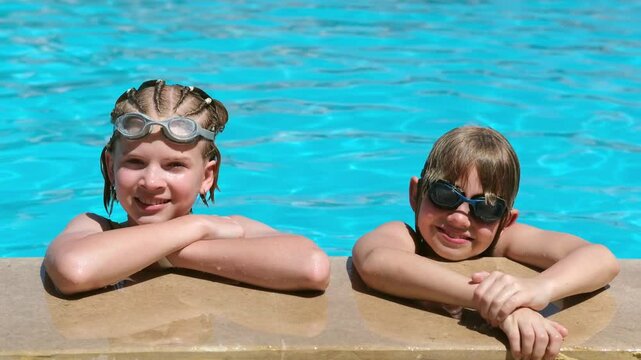 Portrait smiling girl and boy in swimming pool, two children in swimming glasses. Summer travel hotel vacation or classes. Kids relaxing in pool, swimming in blue water. activity, watersports.