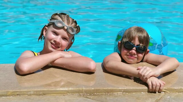 Portrait smiling girl and boy in swimming pool, two children in swimming glasses. Summer travel hotel vacation or classes. Kids relaxing in pool, swimming in blue water. activity, watersports.