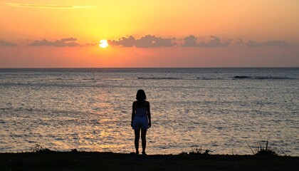 Fototapeta premium 黄金色に染まる夕暮れ時、砂の岬の端に立つ人影が静かな沖縄の海を見つめる。暖かな夏の夕焼け空が燃え上がり、心に響く穏やかで反射的な静寂の時間が広がる情景