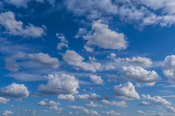 Delicate fluffy cumulus clouds drift across a serene blue sky, creating a peaceful and airy atmosphere in this minimal natural landscape.