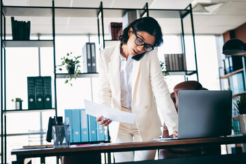 Confident Businesswoman in Office Wearing Elegant Formalwear and Managing Workload on Phone Call at...